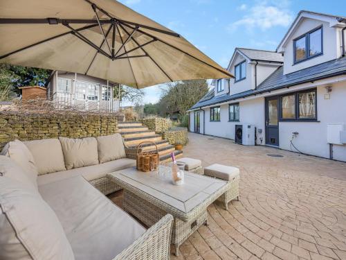 a patio with a couch and a table with an umbrella at Amaranth in Shurdington