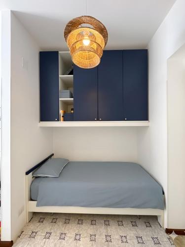 a bedroom with a blue bed and a chandelier at VitaDaMare in Giardini Naxos