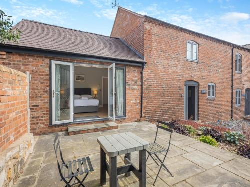 a patio with a table and chairs in front of a brick building at Y Stabl - Uk12742 in Acrefair