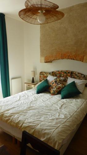 a bedroom with a bed with green and white pillows at Le logis de Presle in Avallon