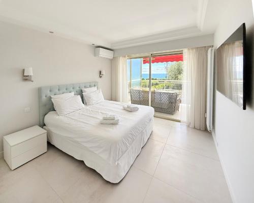 a white bedroom with a bed and a balcony at Elegant 2 Br with parking in Cannes
