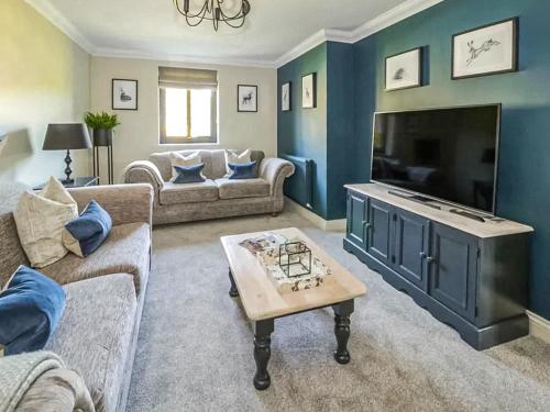 a living room with blue walls and a large television at Garth End in Appleby