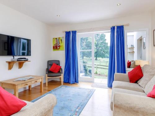 a living room with blue curtains and a tv at The Bothy in Mathon