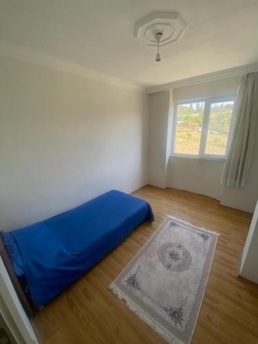 a bedroom with a blue bed and a window at Daily airport aparthotel in Taşoluk