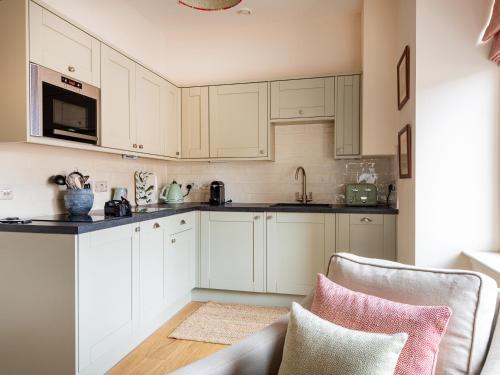 a kitchen with white cabinets and a sink and a couch at Tree House - Uk7556 in Inverness