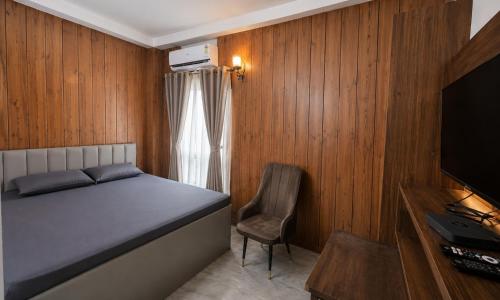 a bedroom with a bed and a chair and a television at Residence Inn in Patna