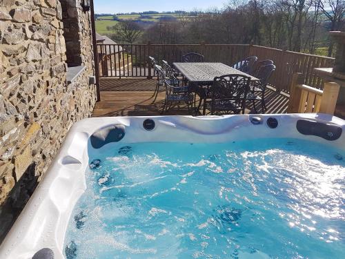 a hot tub in a patio with a table and chairs at The Mill - Om3 in Mydroilin