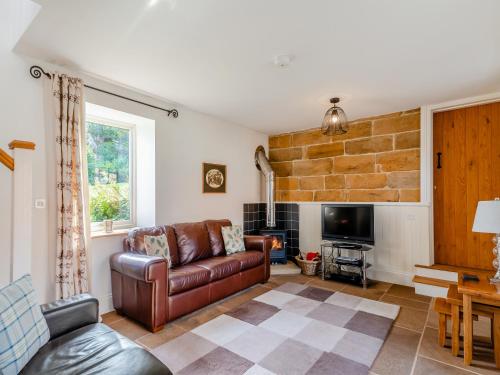 a living room with a leather couch and a tv at Coltus Lands in Castleton