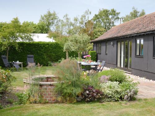 a garden with a table and chairs in front of a house at The Stables in Occold