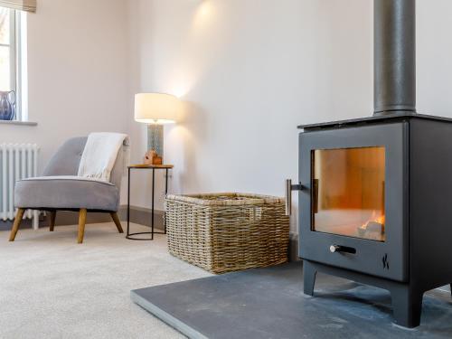 a living room with a fireplace and a chair at The Hayloft - Uk34565 in Whitchurch