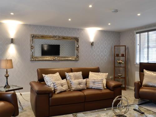 a living room with a brown couch and a mirror at Apple Tree House in Dalry