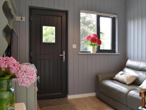 a living room with a door and a couch at Ponsford Ponds Jacks Shepherd Hut - Bcponhut in Cullompton