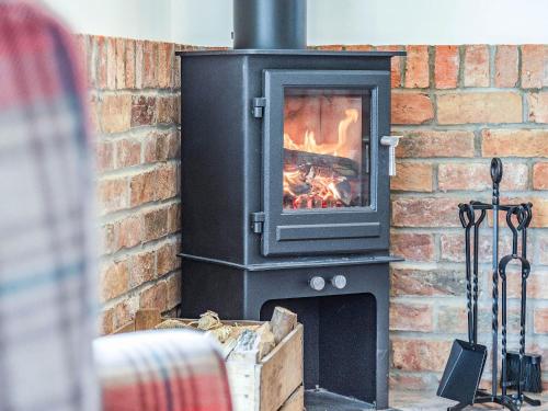 a brick fireplace with a fire in it at The Old Stables - Uk37000 in Ridlington