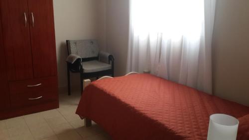 1 dormitorio con 1 cama, 1 silla y 1 ventana en Apart Salta en Salta