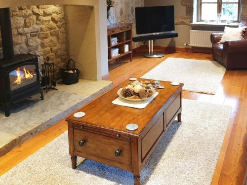 a living room with a coffee table and a fireplace at Flatts Barn in Hebden