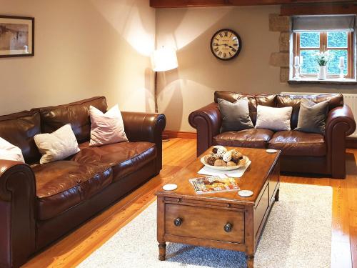 a living room with two leather couches and a coffee table at Flatts Barn in Hebden