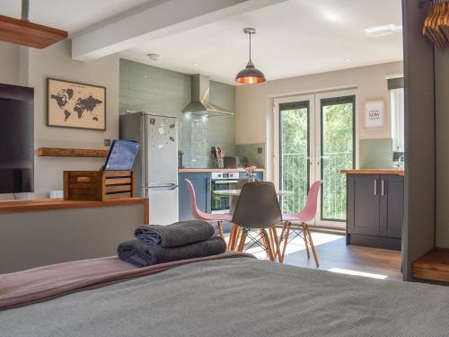 a bedroom with a bed and a kitchen with pink chairs at Willows View in Etchingham