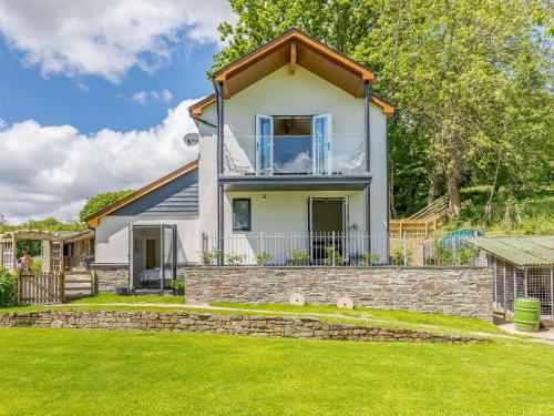 a house with a stone retaining wall in front of a yard at Barn Owls Rest in Clyro