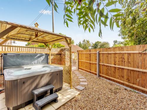 a hot tub in a backyard with a wooden fence at Woodpecker Barn - Uk38613 in Wisbech