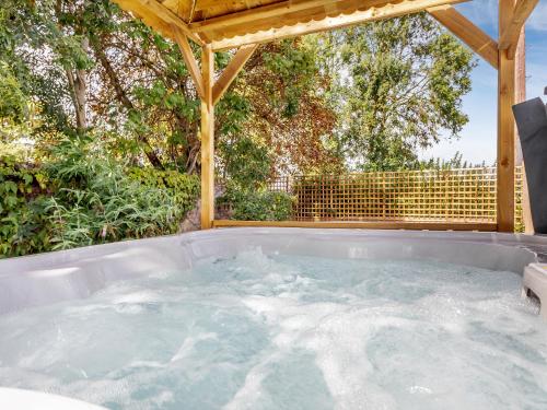 a hot tub in a backyard with a pergola at Woodpecker Barn - Uk38613 in Wisbech