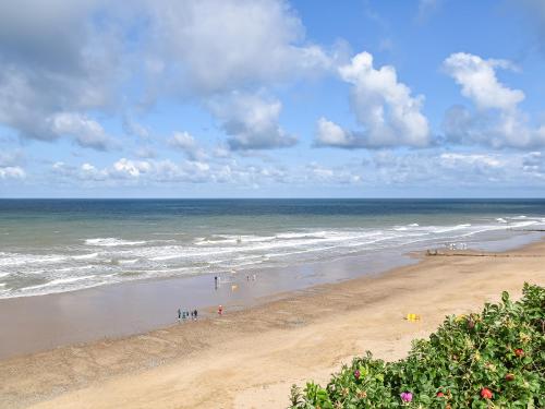a beach with people walking on the sand and the ocean at The Old Barn in Mundesley