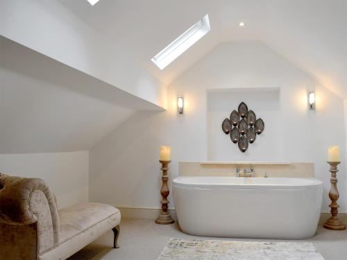 a bathroom with a large white tub and a chair at Clawdd Gwyn in Llanrwst