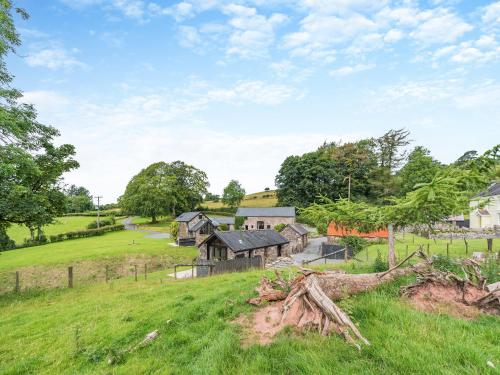 an image of a farm with a field and buildings at Y Bwthyn-Oxm in Gwynfe