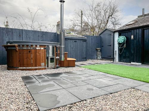 a backyard with a hot tub and a fence at Logiemar Cottage in Ballater