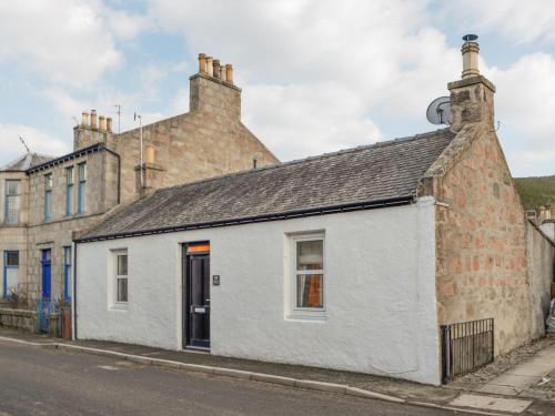 an old white building on the side of a street at Logiemar Cottage in Ballater