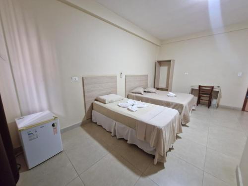 a room with two beds and a small refrigerator at Hotel Dom Mineiro in Curvelo