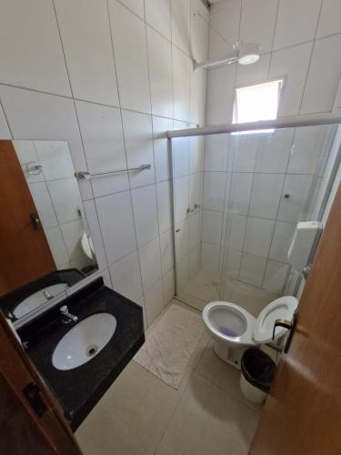 a white bathroom with a sink and a toilet at Hotel Dom Mineiro in Curvelo