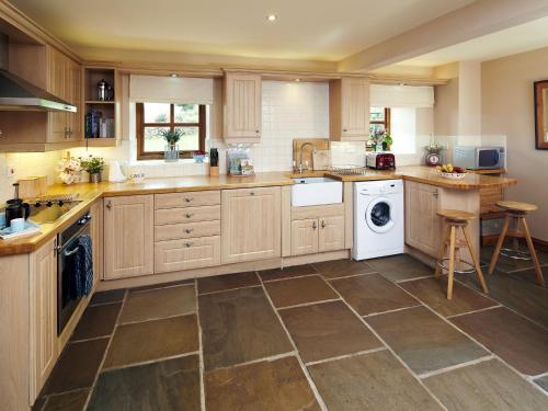 a kitchen with wooden cabinets and a washer and dryer at Birch Cottage - Uk4185 in Hazlehead Bridge