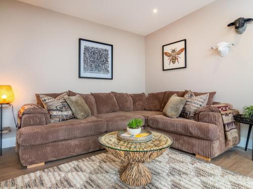 a living room with a brown couch and a table at The Granary - Uk48622 in Buchlyvie
