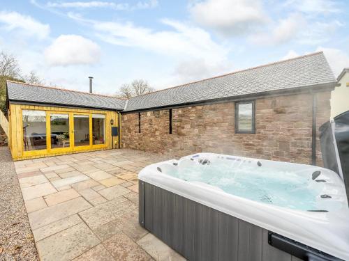 a large hot tub in a yard next to a building at Tyr Ywen Cottage in Abergavenny