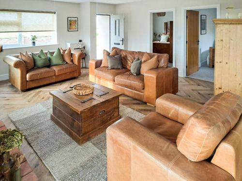 a living room with leather couches and a table at Normandy in Wyberton