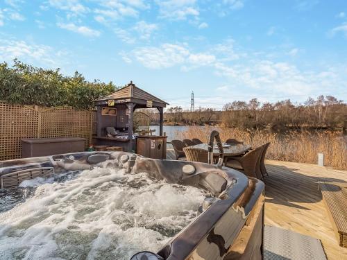 a hot tub on a deck with water at Malibu Lakehouse in Pentney