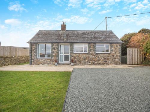 a stone house with white windows on a driveway at Swyn Y Don in Llanfair