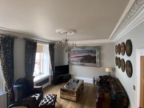 a living room with a couch and a chandelier at Clan Young Suite in Berwick-Upon-Tweed