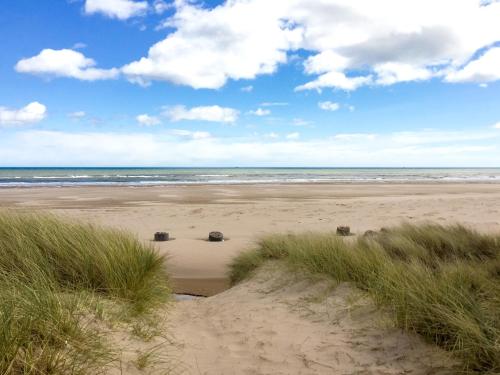 a sandy beach with some grass and the ocean at Drums Beach House in Foveran