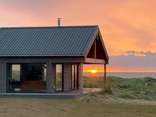 a small house with the sunset in the background at Drums Beach House in Foveran