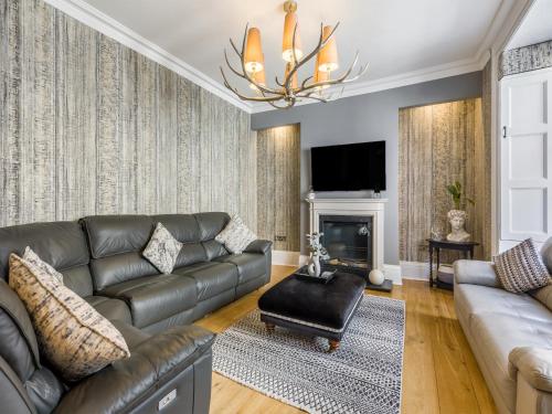 a living room with a leather couch and a chandelier at No3 On The Severn in Bridgnorth