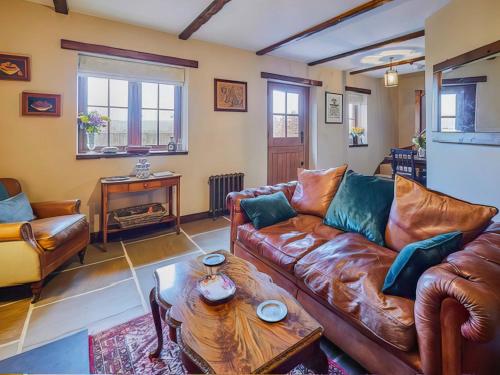 a living room with a leather couch and a table at Rustic Retreat in Llangadog
