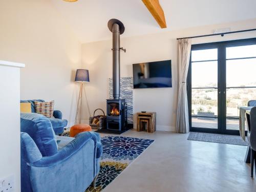 a living room with blue chairs and a fireplace at The Old Cowshed in Porchfield