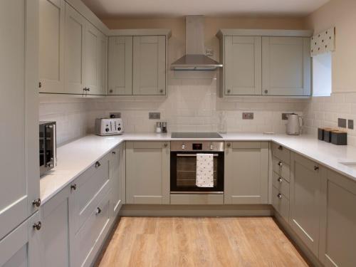 a kitchen with white cabinets and a stove top oven at Drumlanrig Mains Cottage - Uk7174 in Carronbridge