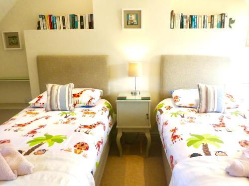 a bedroom with two beds and a table with a lamp at The Owl House in Bishops Waltham