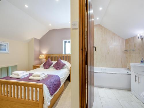 a bedroom with a bed and a bathroom with a tub at Rhandir Barn in Ffair-fâch