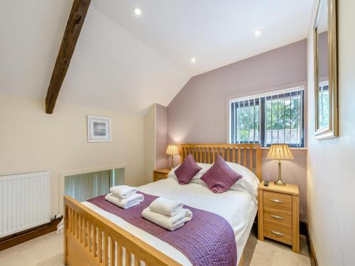 a bedroom with a large bed with purple pillows at Rhandir Barn in Ffair-fâch