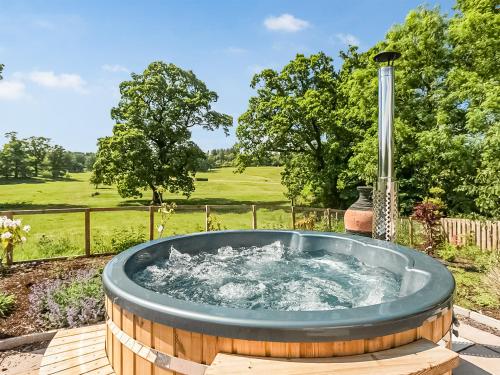 a hot tub on a deck in a yard at Slatehouse Cottage - Uk7562 in Carronbridge