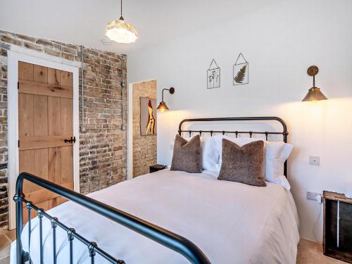 a bedroom with a bed and a brick wall at The Ostlers Cottage in Sleaford