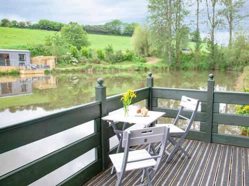 a table and chairs on a deck next to a river at Mallard Roundhouse - Uk33891 in Cullompton